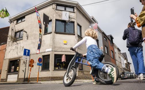 een kind op de fiets kijkt naar het Kunstwerk "Vlaggenmasthouders" 