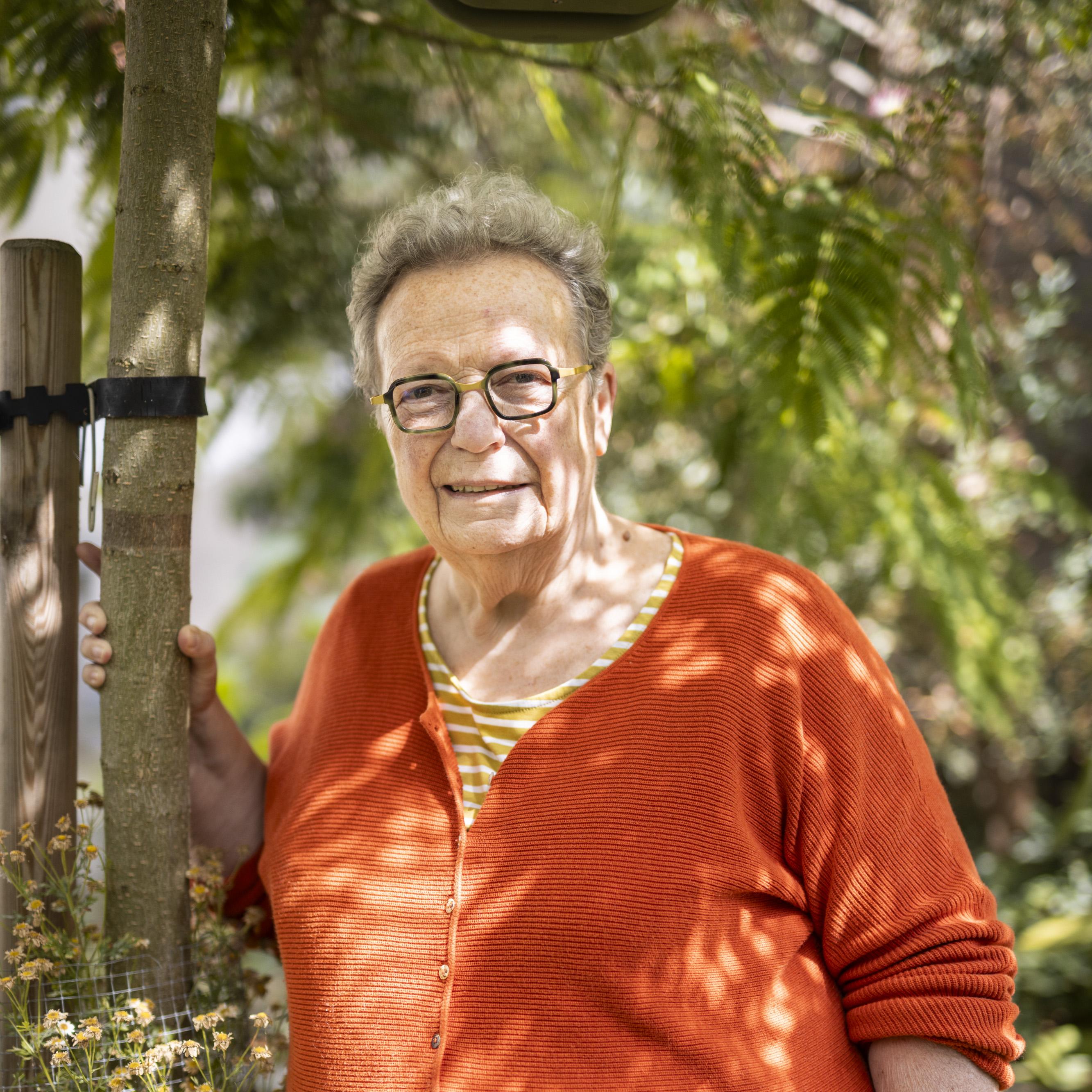 Vrouw in oranje trui die tussen groen staat